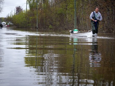 Yann Jodoin pulls his boat along Rue de Versailles, heading to his rental property on boulevard Hurtubise. The water levels are continuing to lower in Gatineau allowing more people to get back to their homes and start the clean up process.   Ashley Fraser/Postmedia