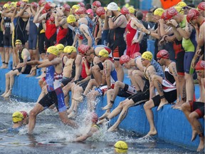 Triathletes enter the water at Dow's Lake for the start of the Ottawa International Triathlon on Sunday. Patrick Doyle/Postmedia