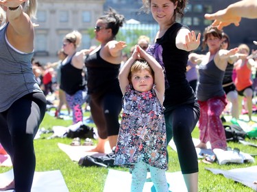 - Little Jane Amoureux, 2, gets a little help from her mom, Emily (centre), while attempting some of the tricky yoga poses.