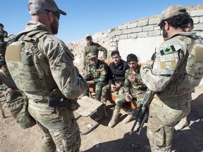 Canadian special forces soldiers, left and right, speak with Peshmerga fighters at an observation post, Monday, February 20, 2017 in northern Iraq.