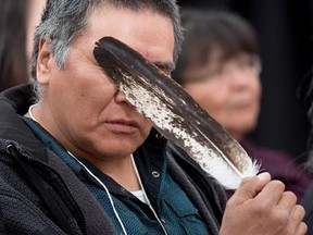 Terry Ladue holds a eagle feather to his face after speaking of his mother Jane Dick Ladue&#039;s murder at the National Inquiry into Missing and Murdered Indigenous Women and Girls taking place in Whitehorse on Thursday, June 1, 2017. THE CANADIAN PRESS/Jonathan Hayward