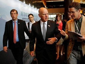 California Gov. Jerry Brown, center, talks with reporters after delivering a speech during the Clean Energy Ministerial International Forum on Electric Vehicle Pilot Cities and Industrial Development, at a hotel in Beijing, Tuesday, June 6, 2017. Brown predicts that President Donald Trump&#039;s decision to pull the U.S. out of the Paris climate accord will prove temporary because of the urgency of the issue. He told The Associated Press on the sidelines of a clean energy conference in Beijing on Tue