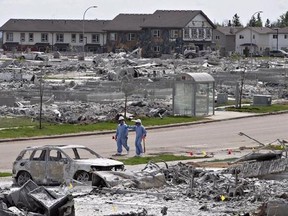 Workers put out markers around a devastated area of Timberlea in Fort McMurray Alta, on Thursday, June 2, 2016. Ontario researchers are finalizing plans to head to Fort McMurray next month to study dust left in homes from the forest fire that ravaged the area last year. THE CANADIAN PRESS/Jason Franson