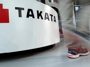 In this May 10, 2017 photo, a visitor walks past the logo of Takata Corp. at a Toyota showroom in Tokyo. Japanese air bag maker Takata Corp. filed for bankruptcy protection in Tokyo on Monday, June 26, 2017 and the U.S., drowned in a sea of lawsuits and recall costs. (AP Photo/Shizuo Kambayashi)