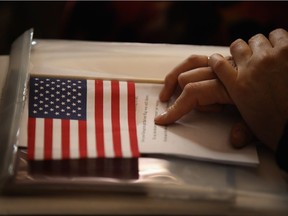 A new U.S. citizen holds an American flag along with her citizenship papers.