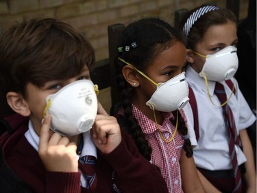 Young children wear protective face masks near the burning 24 storey residential Grenfell Tower block in Latimer Road, West London on June 14, 2017 in London, England.  The Mayor of London, Sadiq Khan, has declared the fire a major incident as more than 200 firefighters are still tackling the blaze while at least 50 people are receiving hospital treatment.