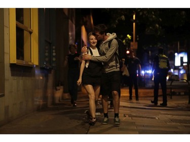 A man kisses a woman about 10 minutes after midnight as they walk away from inside a police cordon.