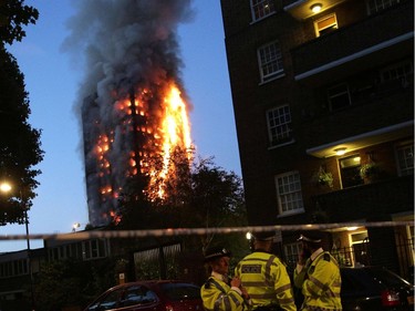 Police man a security cordon as a huge fire engulfs the Grenfell Tower early June 14, 2017 in west London.  The massive fire ripped through the 27-storey apartment block in west London in the early hours of Wednesday, trapping residents inside as 200 firefighters battled the blaze. Police and fire services attempted to evacuate the concrete block and said "a number of people are being treated for a range of injuries", including at least two for smoke inhalation.