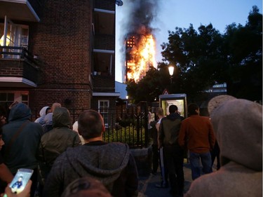 Local residents watch as Grenfell Tower is engulfed by fire on June 14, 2017 in west London.  The massive fire ripped through the 27-storey apartment block in west London in the early hours of Wednesday, trapping residents inside as 200 firefighters battled the blaze. Police and fire services attempted to evacuate the concrete block and said "a number of people are being treated for a range of injuries", including at least two for smoke inhalation.