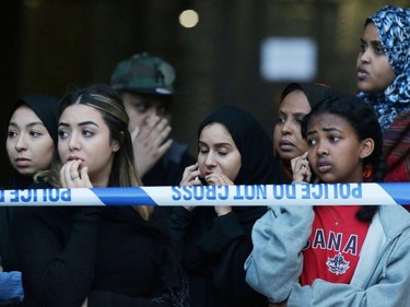 Local residents watch as Grenfell Tower is engulfed by fire on June 14, 2017 in west London.  The massive fire ripped through the 27-storey apartment block in west London in the early hours of Wednesday, trapping residents inside as 200 firefighters battled the blaze. Police and fire services attempted to evacuate the concrete block and said "a number of people are being treated for a range of injuries", including at least two for smoke inhalation.