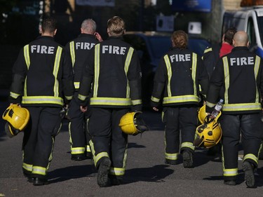 Members of the Fire Brigade walk near Grenfell Tower, a residential block of flats in west London on June 14, 2017, as firefighters continue to control a fire that started in flats in the early hours of the morning. At least six people were killed Wednesday when a massive fire tore through a London apartment block in the middle of the night, with witnesses reporting terrified people had leapt from the 24-storey tower.