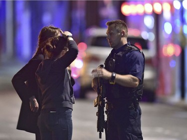 An armed police officer talks to members of the public outside London Bridge Hospital.