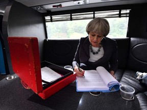 British Prime Minister Theresa May works on the election campaign bus, commonly known as the "Battle Bus", as it travels through Staffordshire in northern England on June 6, 2017. Britain goes to the polls on June 8 to vote in a general election only days after another terrorist attack on the nation's capital. /