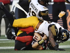 Ottawa Redblacks quarterback Drew Tate gets thumped by Ticats defenders during Thursday's CFL preseason game. Tate received a hit to the head and was removed from the game for examination under the CFL concussion protocol.
