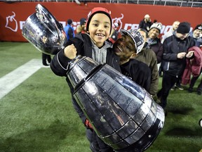 Damaso Munoz and his son, Maddix, celebrate the Redblacks' Grey Cup game victory against the Stampeders in Toronto last November.