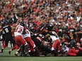 Redblacks linebacker Taylor Reed (44) reaches over players to try and strip the ball from Stampeders quarterback Andrew Buckley  on a third-down gamble in the first half on Friday night. THE CANADIAN PRESS/Justin Tang