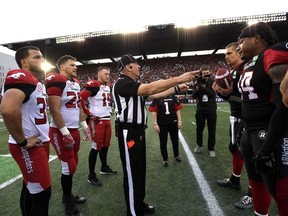 Head referee Kim Murphy conducts the coin toss before the start of Friday's game between the Stampeders and Redblacks at TD Place stadium. THE CANADIAN PRESS/Justin Tang