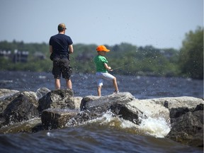 Francois Brosseau and his son seven-year-old Felix Brosseau cast their fishing lines off the rock wall at Britannia Park Sunday June 11, 2017. The city's first heat warning of 2017 rolled in on Sunday with temperatures expected to steadily climb and hit 31 degrees C.  Ashley Fraser/Postmedia