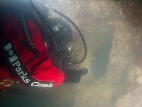 A Parks Canada archaeologist at the stern of the HMS Terror wreck looks through one of the captain's cabin windows.