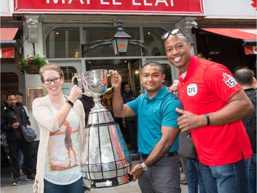 Master Seaman Clarisa Smallwood of Mount Pearl, N.L., and Master Seaman Kyaw San Myint of Surrey, B.C., pose with former CFL quarterback Henry Burris outside the Maple Leaf Sports Bar and Grill in central London on Friday. Jim Ross/CFL