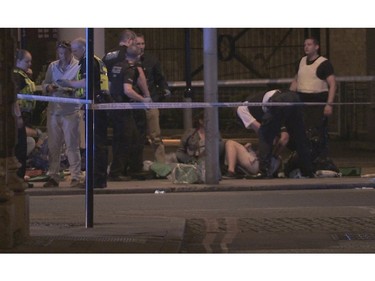 In this image made from PA Video footage, people receive medical attention in Thrale Street near London Bridge.