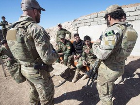 This file photo shows Canadian special forces soldiers, left and right, speaking with Kurdish Peshmerga fighters at an observation post on February 20, 2017 in northern Iraq.