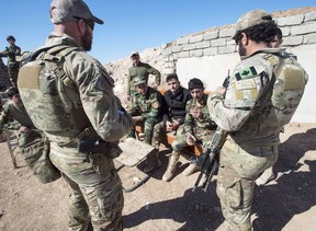 This file photo shows Canadian special forces soldiers, left and right, speaking with Kurdish Peshmerga fighters at an observation post on February 20, 2017 in northern Iraq.