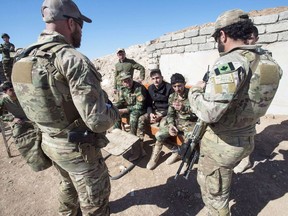 Canadian special forces soldiers, left and right, speak with Peshmerga fighters at an observation post, Monday, February 20, 2017 in northern Iraq. The federal government says the Canadian military will remain in Iraq for at least two more years as part of an international coalition.