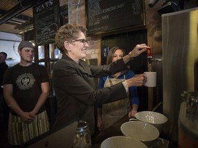Ontario Premier Kathleen Wynne makes herself a cup of tea at a Toronto coffee shop. This was back in 2014, when the Liberals announced a minimum wage hike. This week, they announced another, that the minimum wage would be catapulted up to $15 per hour.