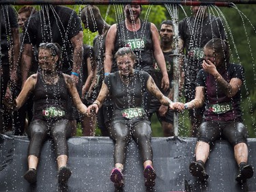 No one was going to finish the Mud Hero obstacles race Sunday June 4, 2017 at Commando Paintball in Navan clean. L-R Sarah Erickson, Olivia Facchin and Susan Philpott hold hands as they get ready to go down the huge mud slide.   Ashley Fraser/Postmedia