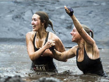 No one was going to finish the Mud Hero obstacles race Sunday June 4, 2017 at Commando Paintball in Navan clean. L-R Corrina Jacob and Roxane Monette were excited after coming down the huge slide into the pool of muddy water.   Ashley Fraser/Postmedia