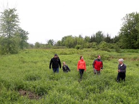 Charles Houle, his wife Cheryle and son Chance stand in parkland behind their home in Navan Ontario Tuesday June 6, 2017. The Houle family and some neighbourhood friends are members of a group of Navan landowners opposing a plan by South Nation Conservation Authority to build three "wetland" pools and a boardwalk on city parkland behind her house on Birchtree Crescent in Navan. Walking with the Houle's is Peter Friske (red jacket on right) and Daniel Charron (right).