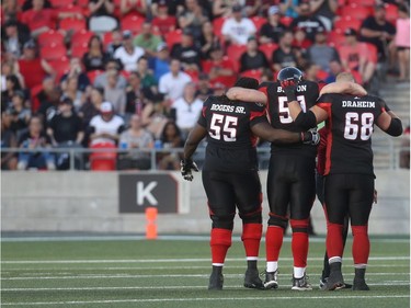 Redblacks offensive lineman Pierce Burton gets helped off by SirVincent Rogers (55) and Tommie Draheim (68) after injuring his left leg during the first half. Tony Caldwell/Postmedia