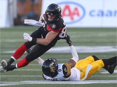 Tiger-Cats defender Travis Lee pulls down Redblacks receiver Riley Wilson after he caught a pass in the first half. Tony Caldwell/Postmedia