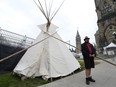 A man stands outside a large teepee erected by indigenous demonstrators to kick off a four-day Canada Day protest in front of Parliament Hill in Ottawa on Thursday, June 29, 2017.