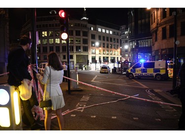 Members of the public look on as a police close off the area by Monument station.