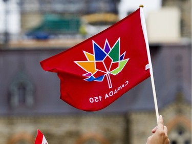 People wave flags on the centre stage on the front lawn of Parliament Hill during Canada Day celebrations in downtown Ottawa Saturday, July 1, 2017.
