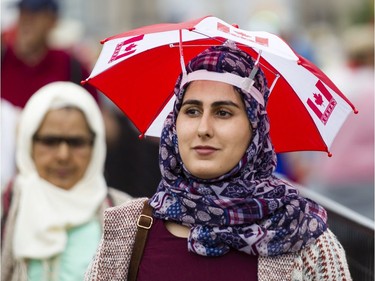 A woman uses an umbrella hat to protect herself from a light rain on Wellington St. during Canada Day celebrations in downtown Ottawa Saturday, July 1, 2017.