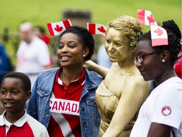 People pose with busker, Daughters of Midas, centre,  during Canada Day celebrations in downtown Ottawa