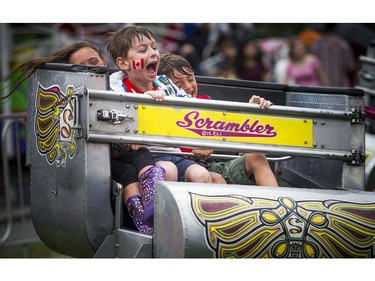 People didn't let the weather stop them from heading out to celebrate Canada Day in Barrhaven at Clarke Fields Saturday July 1, 2017. L-R eight-year-old Madeline Nieuwoudt, eight-year-old Jack Duncan and six-year-old Ben Nieuwoudt were all smiles as they hit up the scrambler twice in a row.