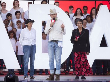 Gord Downie of The Tragically Hip stands between Daisy Wenjack, left, and Pearl Wenjack on the stage during WE Day Canada on Parliament Hill on Sunday.