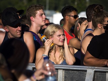 A young woman covers her ears as a band performed on the City Stage at RBC Bluesfest.