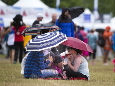 People found a dry spot under some umbrellas at RBC Bluesfest Sunday July 9, 2017.