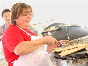 Despite the heat in the outdoor kitchen, Yvette Gharib, happily cooks up tasty "saj" bread lathered in garlic and thyme, and served with cucumbers.