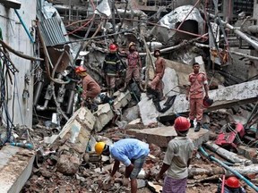 Bangladeshi firefighters and rescuers stand on the debris after a Monday evening boiler explosion at a garment factory owned by export-oriented Multifabs Ltd. at Kashimpur area in Gazipur district, outside capital Dhaka, Bangladesh, Tuesday, July 4, 2017. (AP Photo/A.M. Ahad)