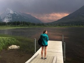 A woman takes in the smoke blanketing Mt. Rundle from a forest fire in Kootenay National park as she stands on a dock on the Vermillion lakes near Banff, Alta. Sunday July 15, 2017. THE CANADIAN PRESS/Adrian Wyld