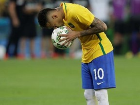 FILE - In this Aug. 20, 2016 file photo, Brazil&#039;s Neymar kisses the ball before scoring the decisive penalty kick during the final match of the mens&#039;s Olympic football tournament at the Maracana stadium in Rio de Janeiro, Brazil. As Rio de Janeiro reels from corruption, rising crime and unfinished infrastructure, its residents can look no further than the iconic image of Neymar to remind them of the Rio de Janeiro Olympics that took place one year ago and the price they payed for hosting the gam