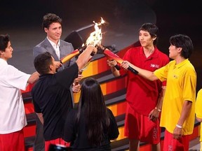 The four sacred fire torches come together to create one flame, and the torch is passed to Prime Minister Trudeau by four indigenous youth at the Canada Summer Games opening ceremony in Winnipeg, Manitoba, Friday, July 28, 2017. THE CANADIAN PRESS/John Woods