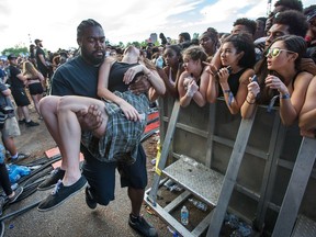 Security carries a young woman from the crushing crowd waiting for Migos as day seven of the RBC Bluesfest takes place on the grounds of the Canadian War Museum.