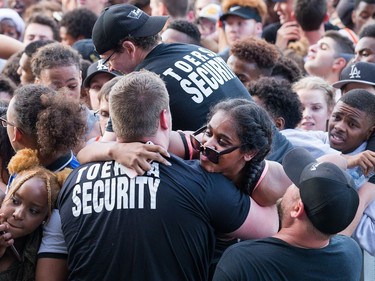 Security helps a woman out of the crushing huge crowd waiting for Migos as day seven of the RBC Bluesfest takes place on the grounds of the Canadian War Museum.